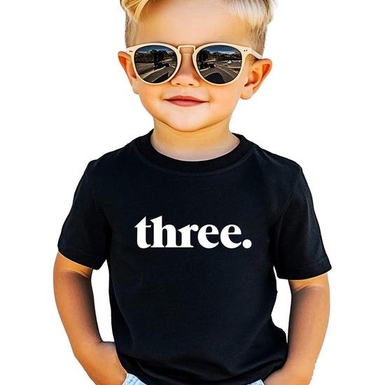 Toddler wearing gray Three period 3rd birthday shirt with minimalist typography