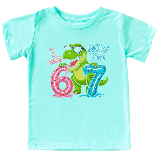 Black dinosaur 7th birthday shirt showing T-Rex design with colorful sprinkled numbers