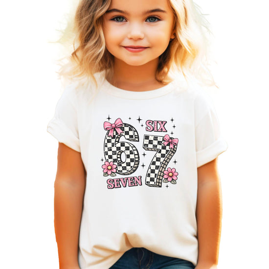 Flat lay of girls birthday shirt showing Six Seven design with pink accents
