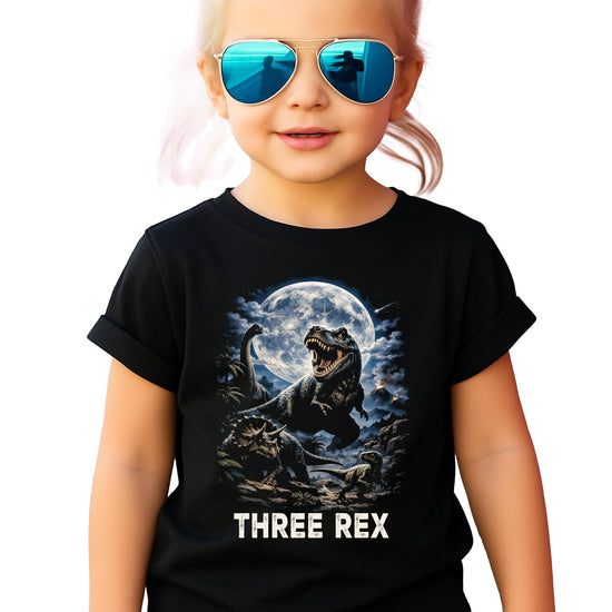 Toddler wearing black Three Rex 3rd birthday dinosaur shirt front view