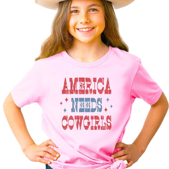 Close-up of America Needs Cowgirls vintage patriotic graphic design on pink tee