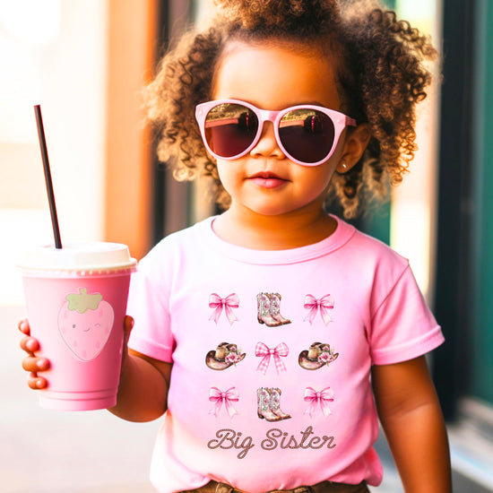 Full view of big sister cowgirl announcement shirt with western boots and bows design