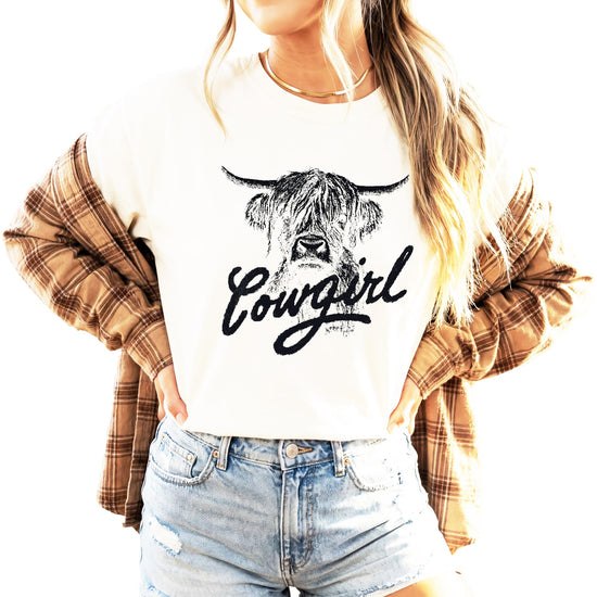 Close-up detail of highland cow design with cowgirl script on blue shirt