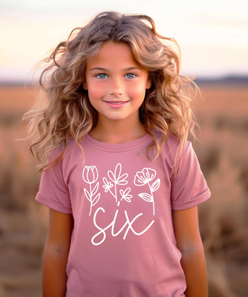 Flat lay styling of floral 6th birthday shirt for toddler girls outfit coordination