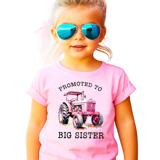 Close-up of pink tractor graphic with promoted to big sister text on shirt