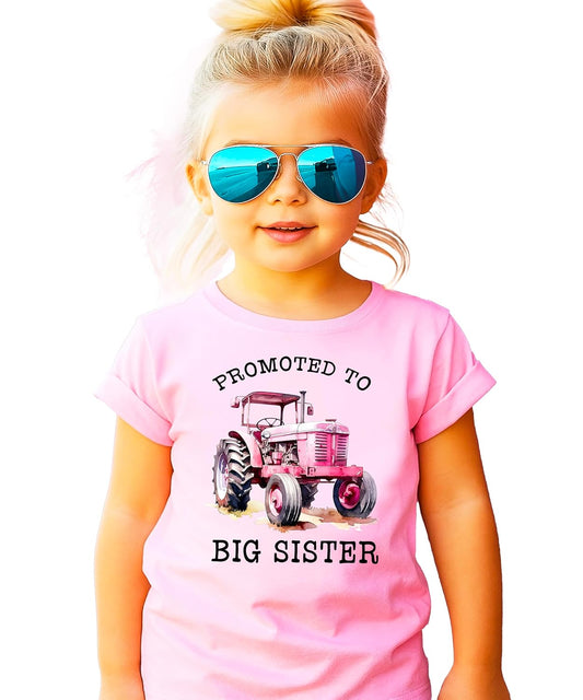 Close-up of pink tractor graphic with promoted to big sister text on shirt