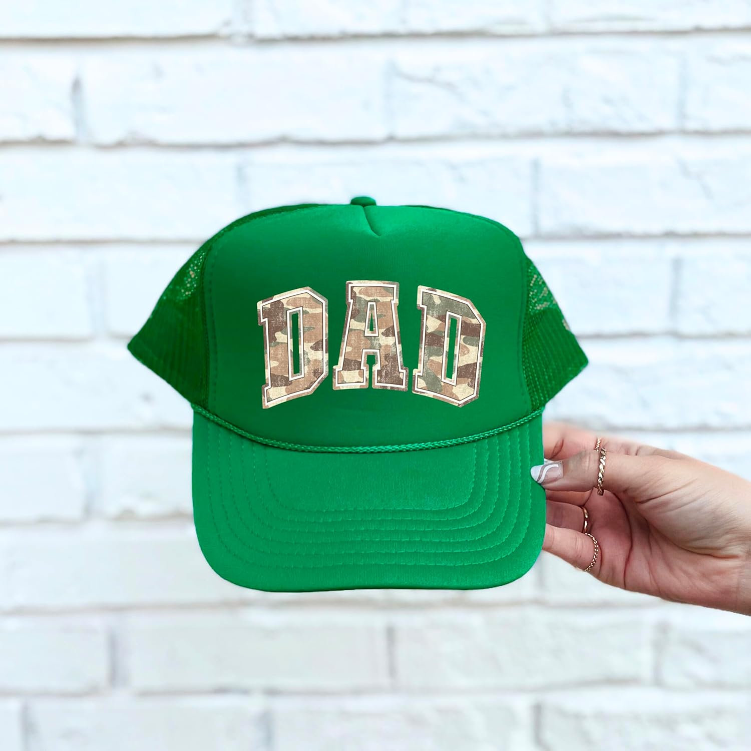 Dad trucker hat product styling shot with camo varsity lettering detail