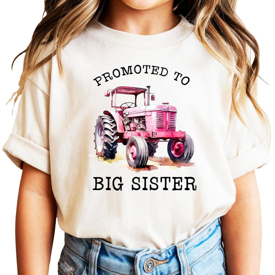 Pink promoted to big sister tractor shirt on young girl outdoors