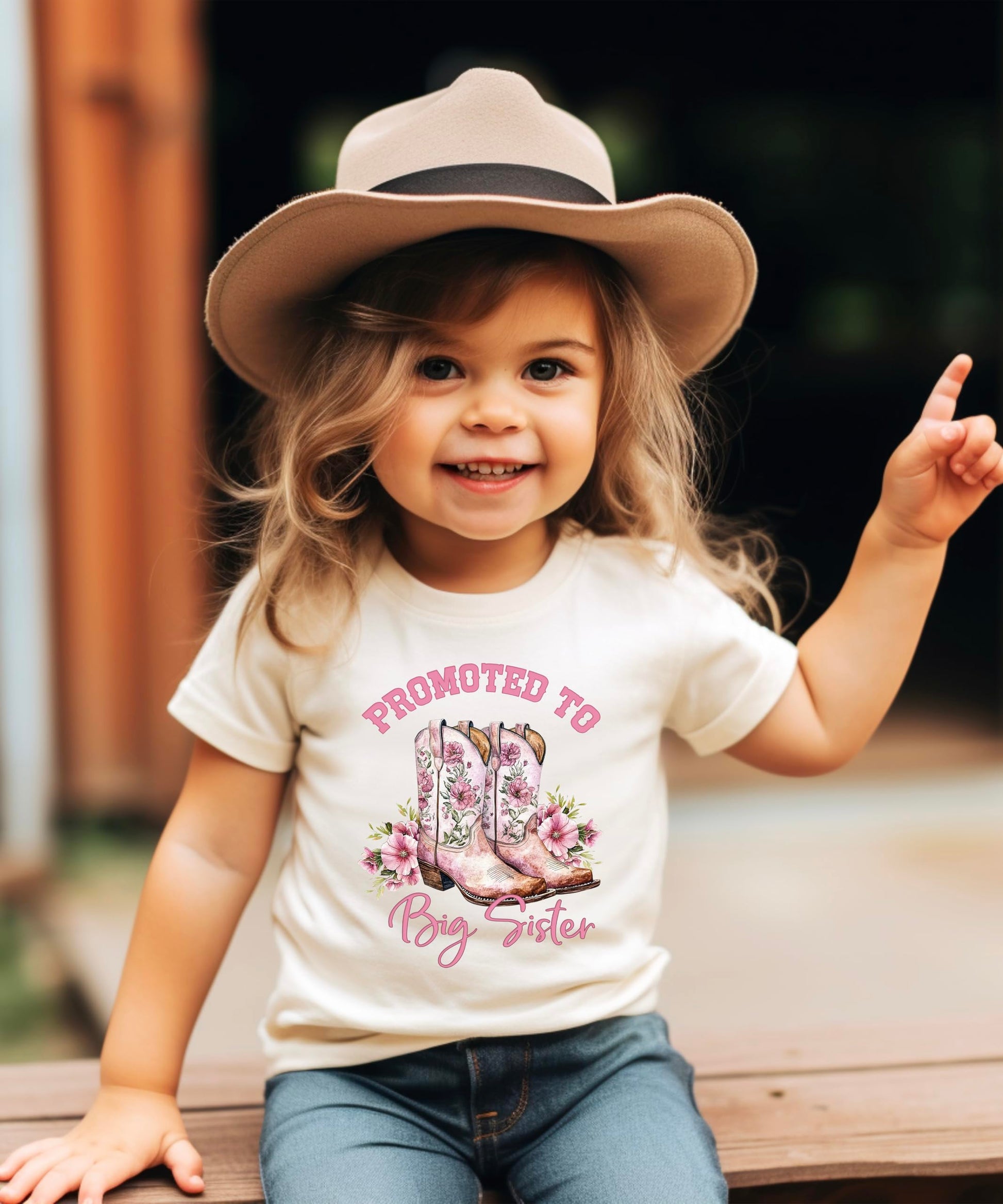 Big Sister shirt flat lay displaying full pink cowgirl boots and floral design
