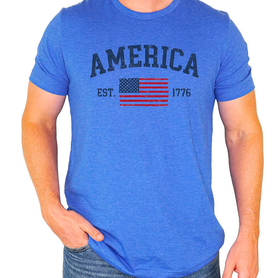 America Est 1776 patriotic shirt flat lay showing vintage American flag design and collegiate lettering