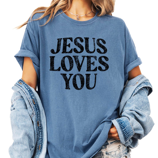 Jesus Loves You distressed graphic shirt in blue jean color displayed on flat surface