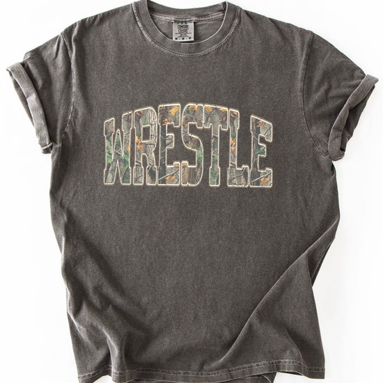 Model wearing camo wrestling graphic tee demonstrating unisex fit