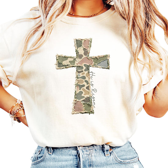 Close-up of He Is Risen cross graphic with colorful patchwork pattern on blue shirt