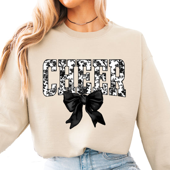 Sand crewneck sweatshirt with black floral CHEER varsity letters and coquette bow, front view