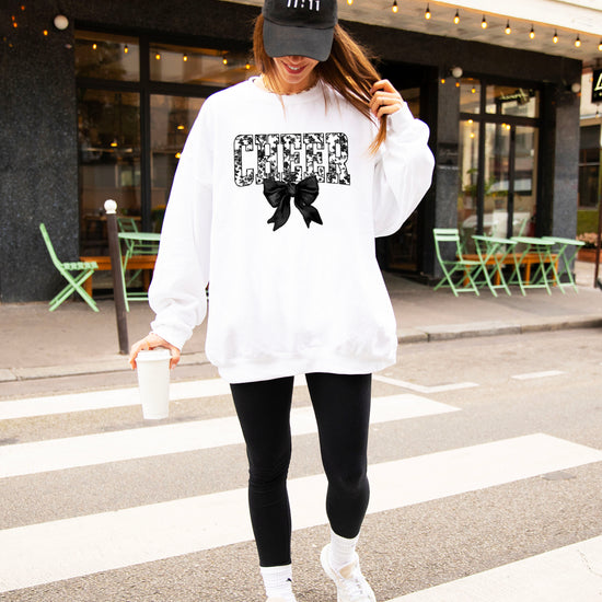 White cheer sweatshirt with black floral bow design, styled view