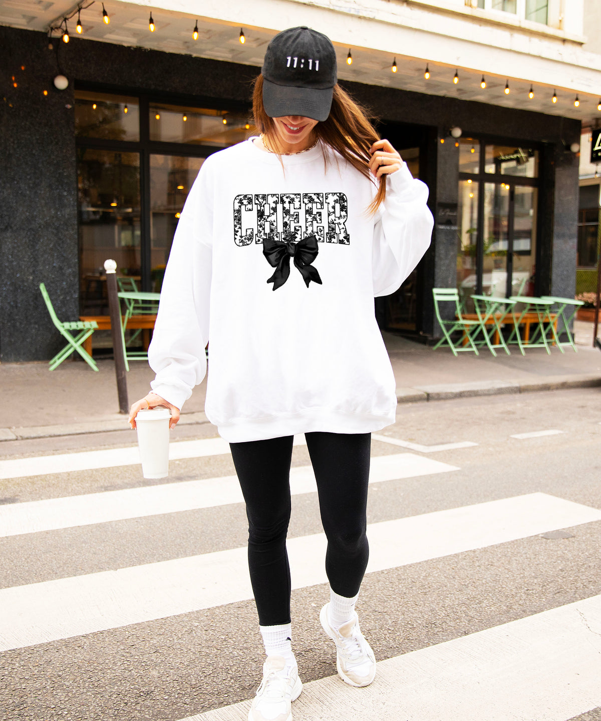 White cheer sweatshirt with black floral bow design, styled view