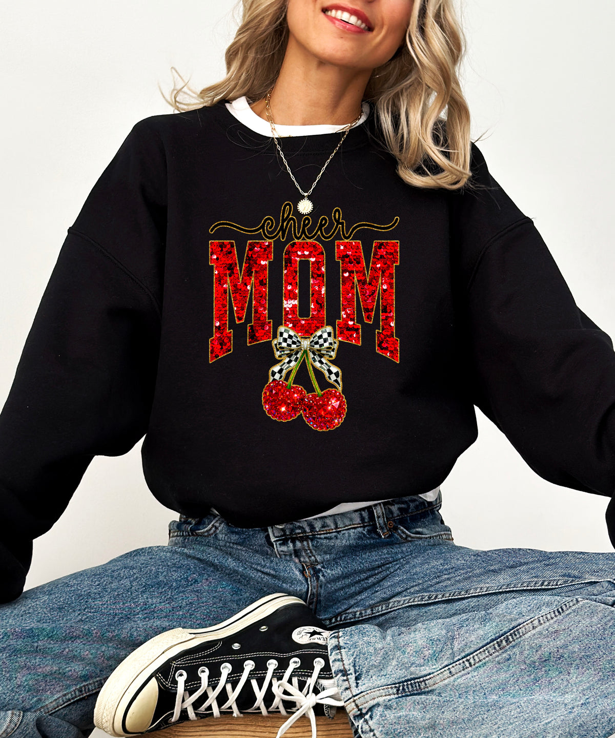 Black Cheerleader Mom crewneck sweatshirt with ink-printed faux sequin cheer script, MOM lettering and cherry coquette bow, styled detail view