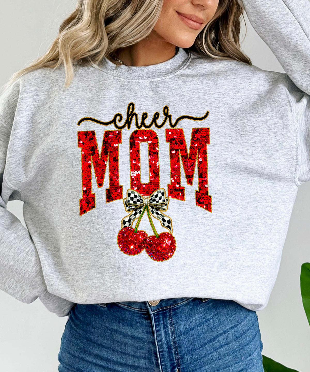 Gray Cheerleader Mom crewneck sweatshirt with ink-printed faux sequin cheer script, MOM lettering and cherry coquette bow, close-up of the ink-printed design