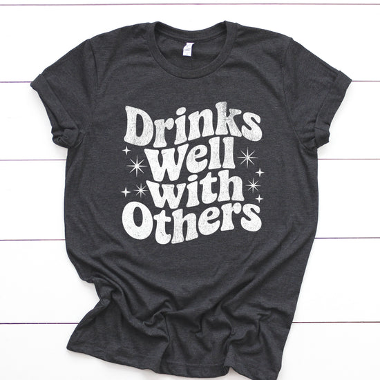 Drinks Well With Others funny graphic tee for women in Dark Gray Heather, lifestyle view