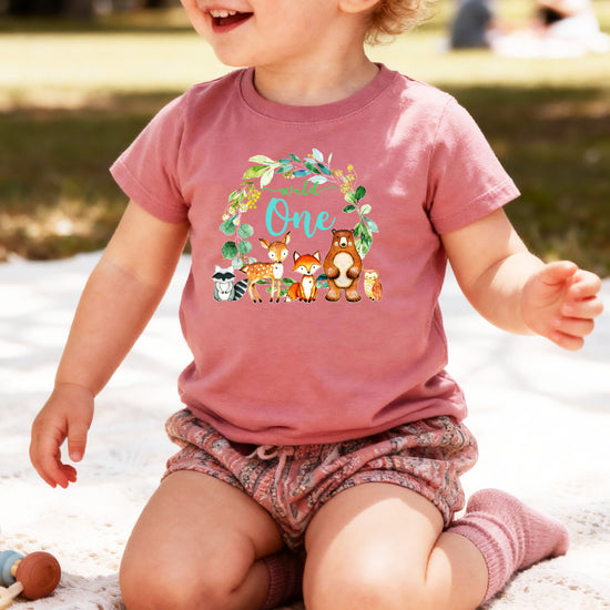 Close-up of Wild One woodland wreath design on mauve baby tee