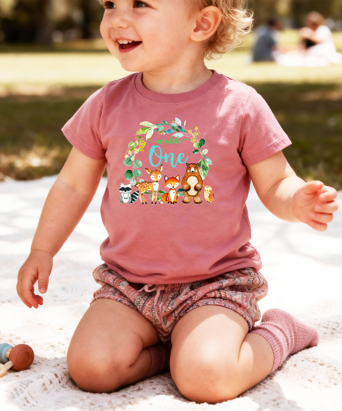 Close-up of Wild One woodland wreath design on mauve baby tee