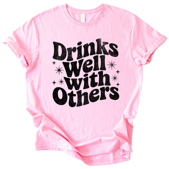 Drinks Well With Others funny graphic tee for women in Pink, lifestyle view