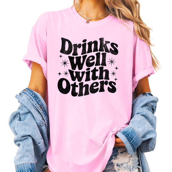 Drinks Well With Others funny graphic tee for women in Pink, back view