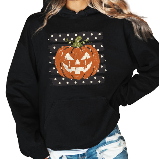 Black hoodie with retro polka dot jack o lantern pumpkin graphic, styled flat lay