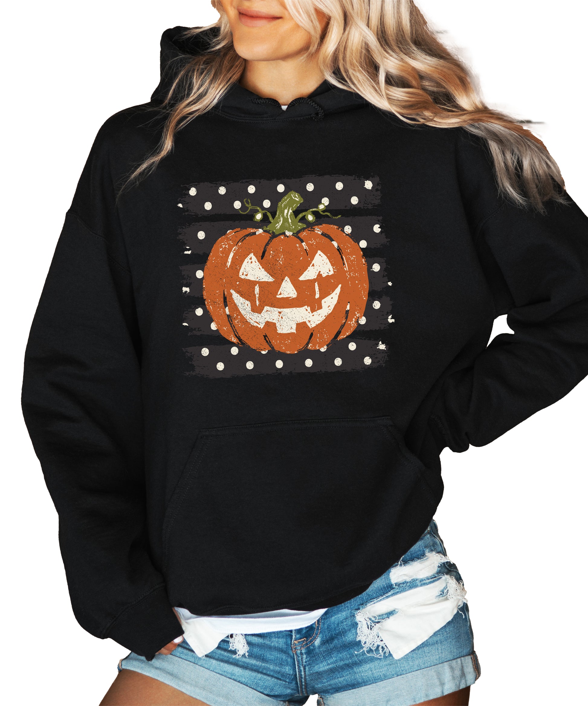 Black hoodie with retro polka dot jack o lantern pumpkin graphic, styled flat lay
