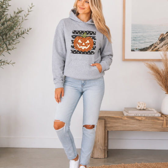 Gray hoodie with retro polka dot jack o lantern pumpkin graphic, styled flat lay