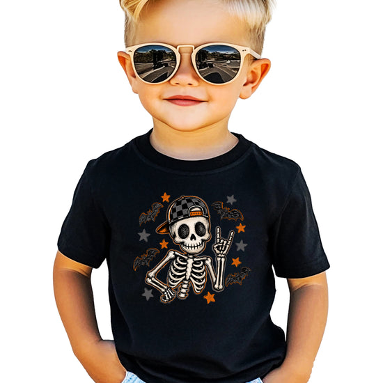 Black skeleton Halloween shirt for boys with rock on hand sign and checkered hat, front view