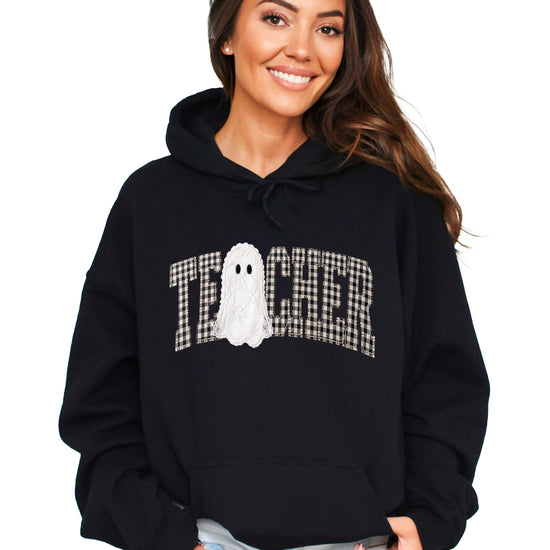 Black hoodie with ink-printed gingham ghost teacher Halloween graphic, front view