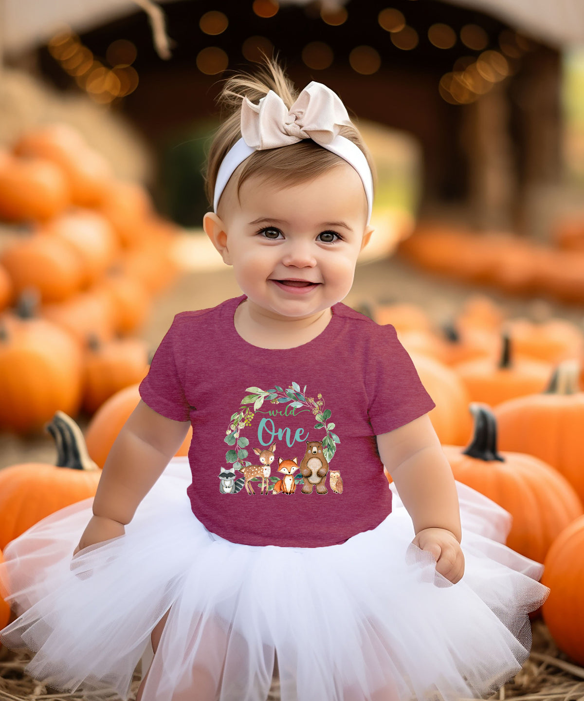 Close-up of Wild One woodland wreath design on vintage burgundy baby tee