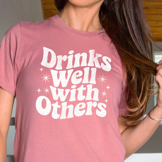 Drinks Well With Others funny graphic tee for women in Mauve, back view