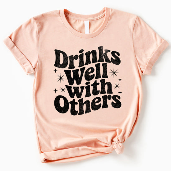 Drinks Well With Others funny graphic tee for women in Peach, lifestyle view