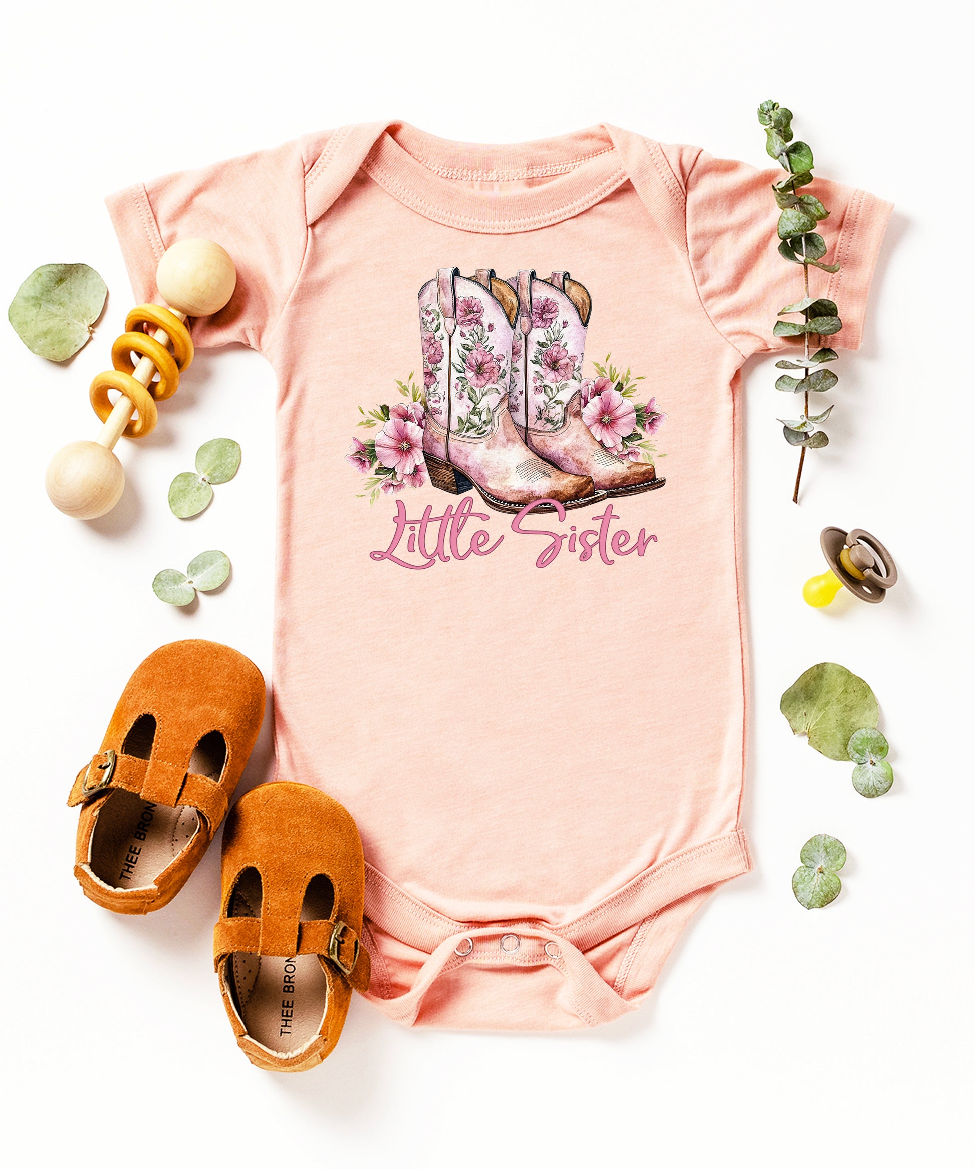 Peach Little Sister bodysuit, styled flat lay
