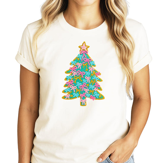 Close-up of Christmas tree ink print with pink bow ornaments and sparkling gold star on kids tee