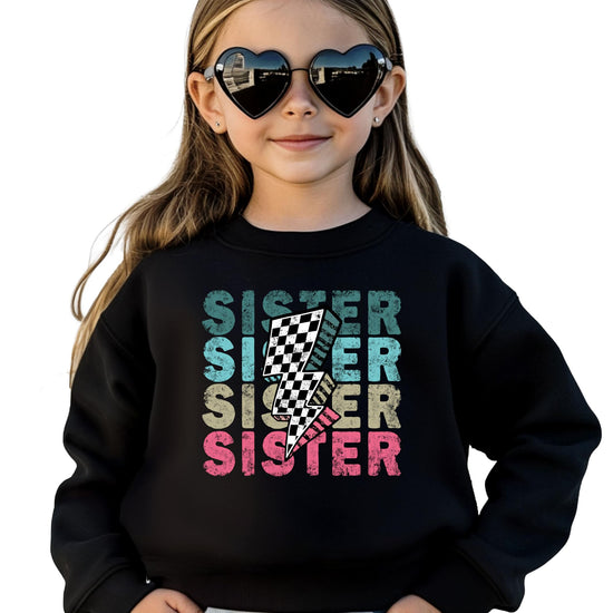 Close-up of colorful SISTER lightning bolt graphic print on pink youth sweatshirt
