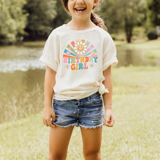 Young girl wearing rainbow sunbeam birthday shirt in peach, retro groovy style