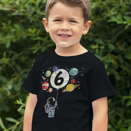 Child wearing 6th birthday space shirt with moon balloon and colorful planet graphics
