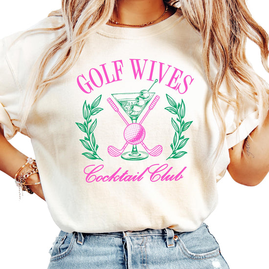 Ivory women's t-shirt with a funny Golf Wives Cocktail Club graphic featuring a dirty martini and crossed golf clubs
