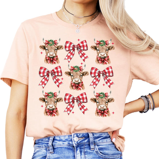 Front view of festive cow holiday graphic t-shirt for women and girls in peach