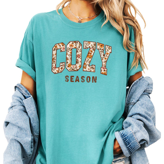 Styled flat lay of Cozy Season ivory fall t-shirt with orange floral graphic