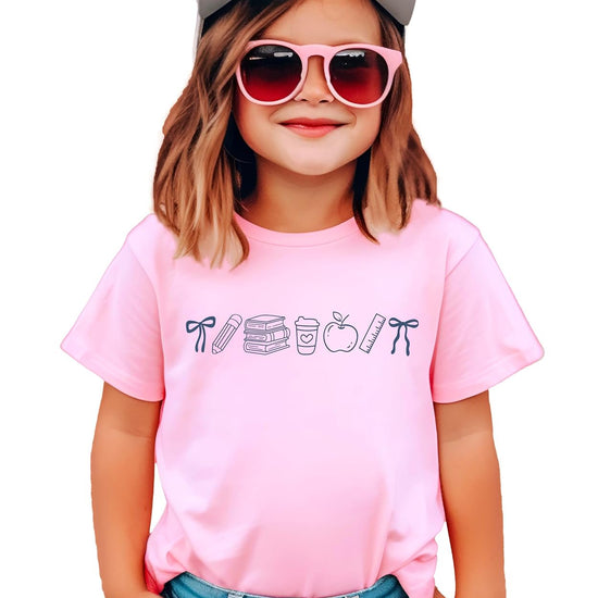 Close-up of coquette bow school supplies screen-printed graphic on pink cotton tee by Olive Loves Apple