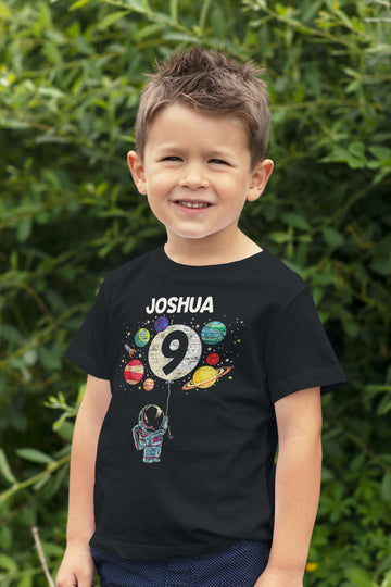 Close-up of 9th birthday astronaut rocket tee print with moon and planets on black youth shirt
