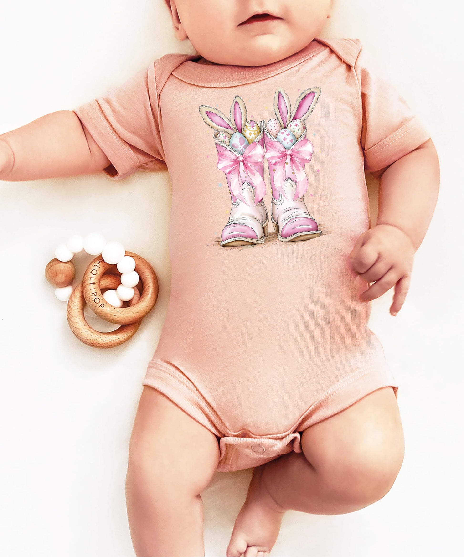 Flat lay of western-themed Easter baby bodysuit in peach and pink tones for newborn girls