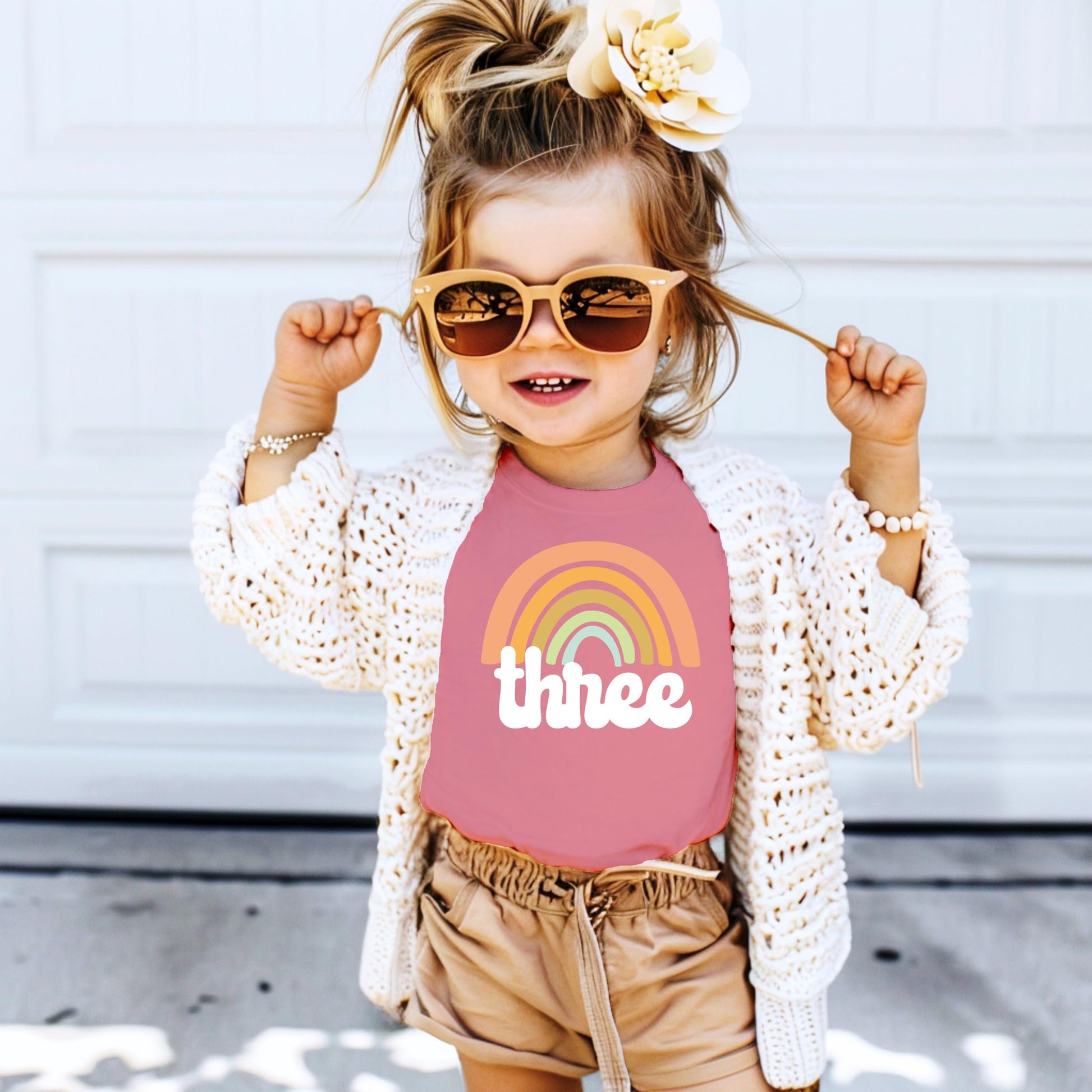 Flat lay of a purple toddler girls retro rainbow third birthday graphic tee