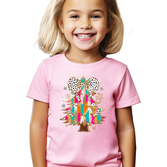 Model wearing pink holiday graphic tee with colorful glitter Christmas tree and coquette bow design