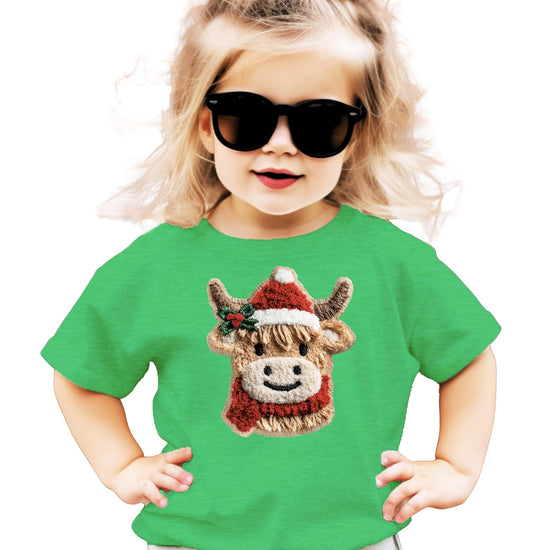 Front view of kids holiday graphic tee featuring a cozy cow in Santa hat on vintage red shirt
