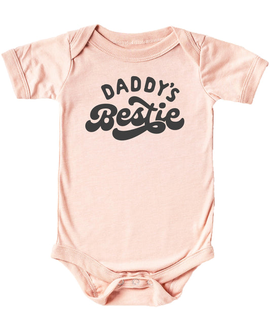 Close-up of Daddy's Bestie retro graphic print on a soft peach baby one-piece bodysuit